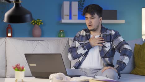 man watching horror movie on laptop at night. the man is frightened and tense.