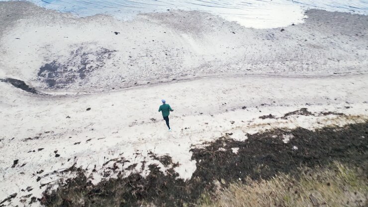 Jogger on a rural trail in an aerial countryside view near the beach on an overcast day