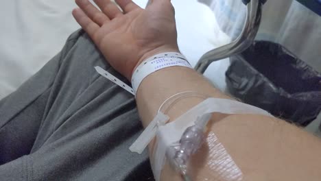 cierre de una vía intravenosa insertada en un brazo derecho masculino no identificable