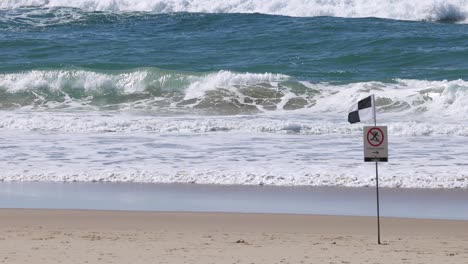 ocean waves hitting the shore with a warning sign