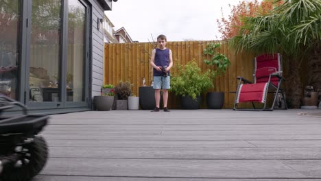 niño en casa al aire libre en el jardín jugando con su coche rc, camión, 4 x 4