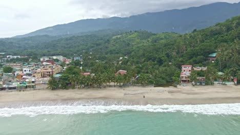 Schöner-Blick-Auf-Den-Strand-Von-Wellen,-Die-Durch-Die-Sandige-Küste-Brechen,-Silhouetten-Von-Bergen-Mit-Einem-Bewölkten-Himmel-Darüber