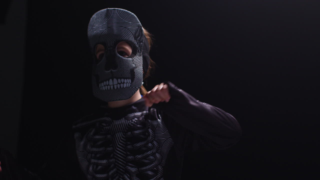 스레톤 의상을 입은 아이가 할로윈에 검은 바탕에 춤을 추는 스튜디오