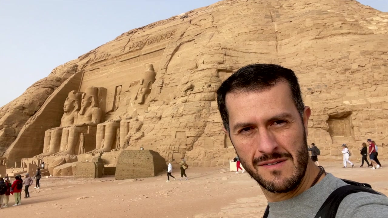 Turista che fa un video selfie fuori dal tempio egizio di Abu Simbel. Viaggiatore che registra un video selfie della statua del Faraone Ramses II in Egitto. Uomo in viaggio di vacanza. Viaggio da influencer. Voglia di viaggiare