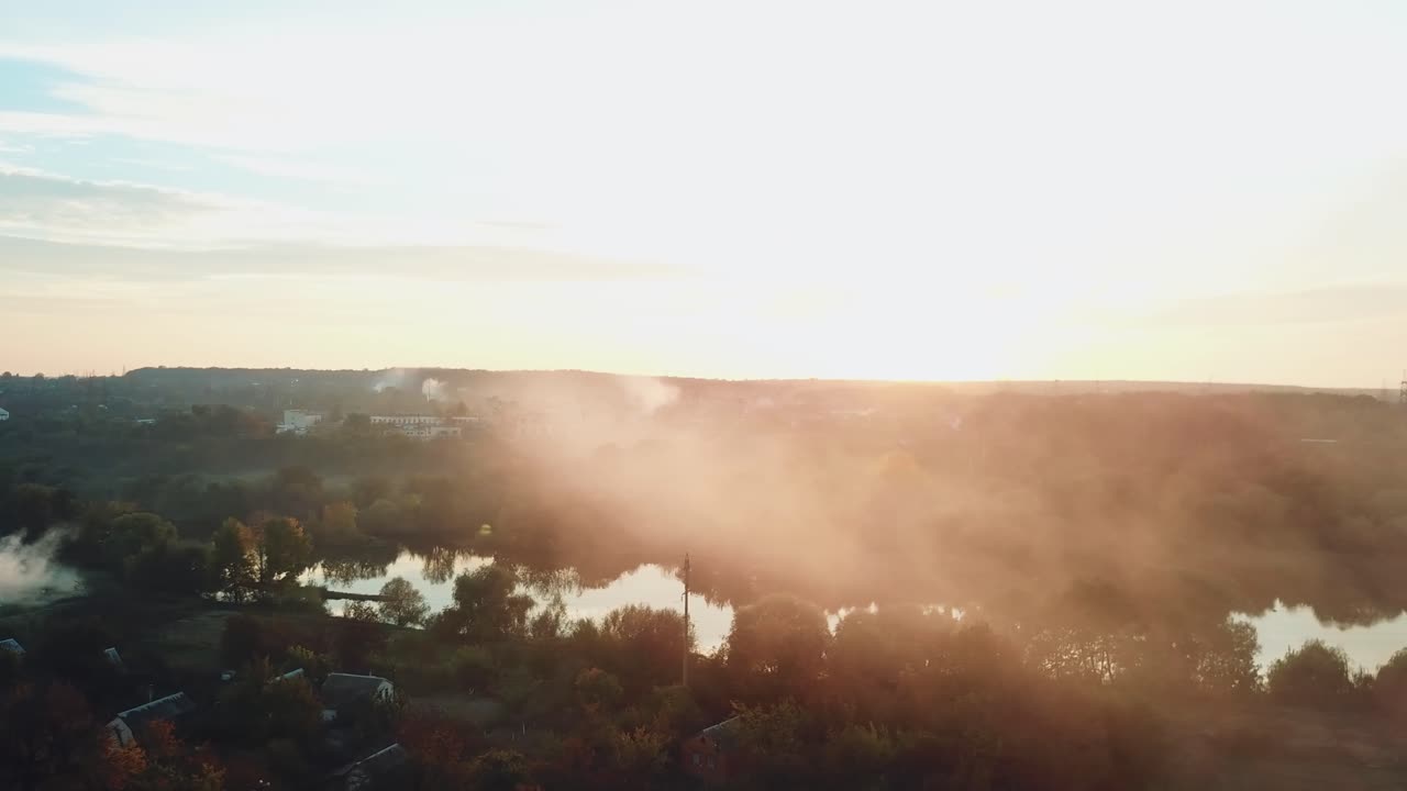 smoke are enveloping a river as a result of a fire after a drought on the background of power station into the distance. Aerial view