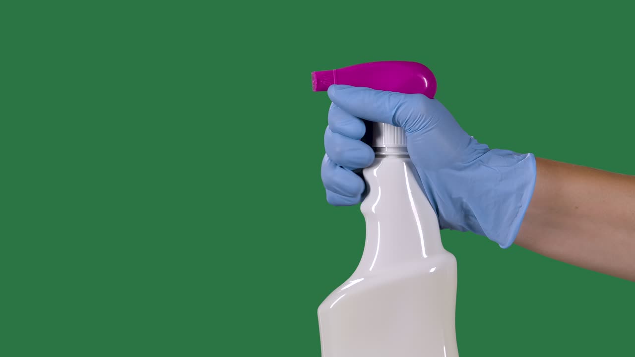hombre con guantes de protección pulveriza un spray higiénico de limpieza para la desinfección y prevención de covid-19. pantalla verde, llave de croma. cámara lenta. primer plano