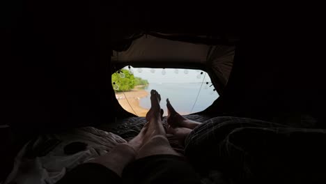 peaceful morning light fills camper tent as couple rests beside calm reservoir