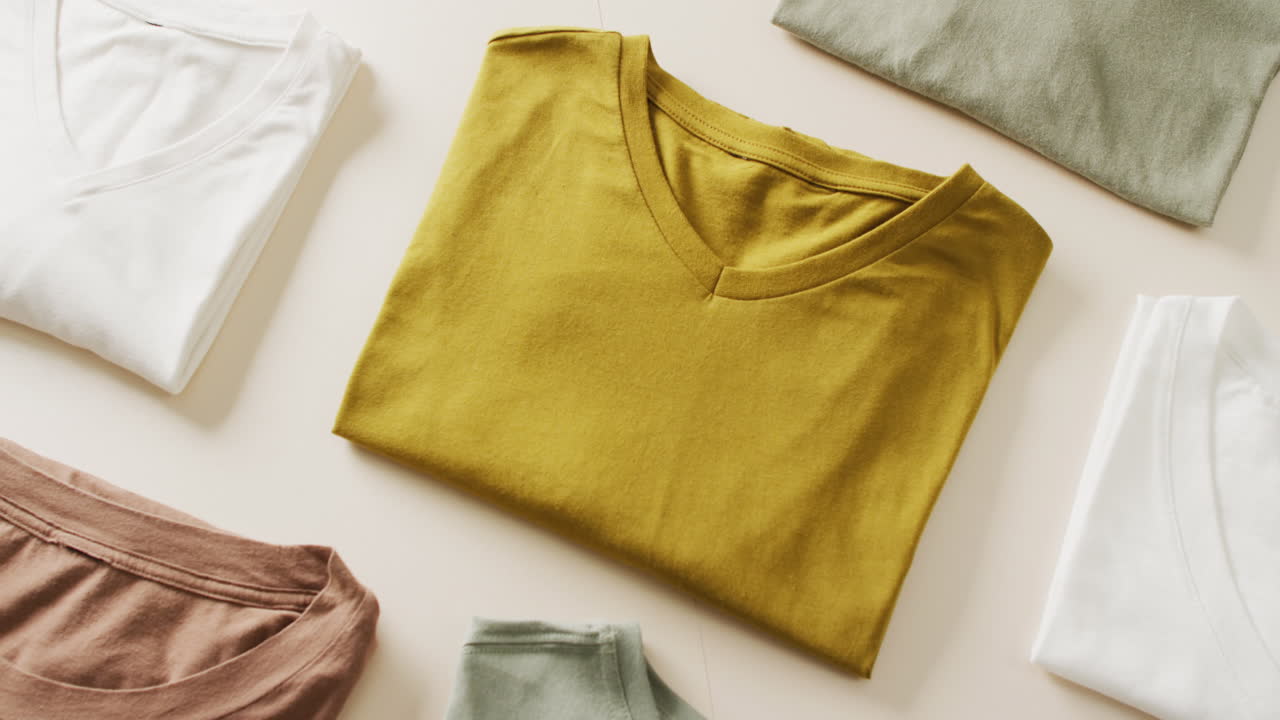 Video of close up of folded t shirts on white background