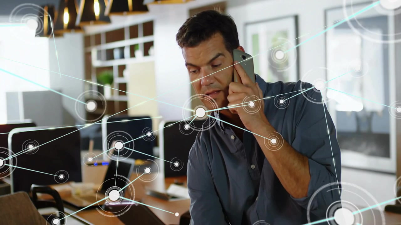 Male pro answering phone in office, checking tablet and causing HUD expanding across tech network