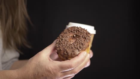 Hands-drinking-take-out-coffee-with-chocolate-doughnut-medium-shot