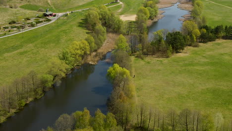 Lone-Person-Walks-By-The-Rivershore-Of-Beautiful-Greenery-Lawn-Of-Myslecinek-Nature-Park-In-Poland