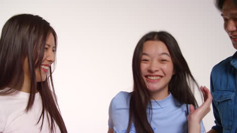 색 스튜디오 배경 앞의 젊은 친구 그룹이 사진 부스 스타일의 초상화를 위해 포즈를 취하고 있습니다.