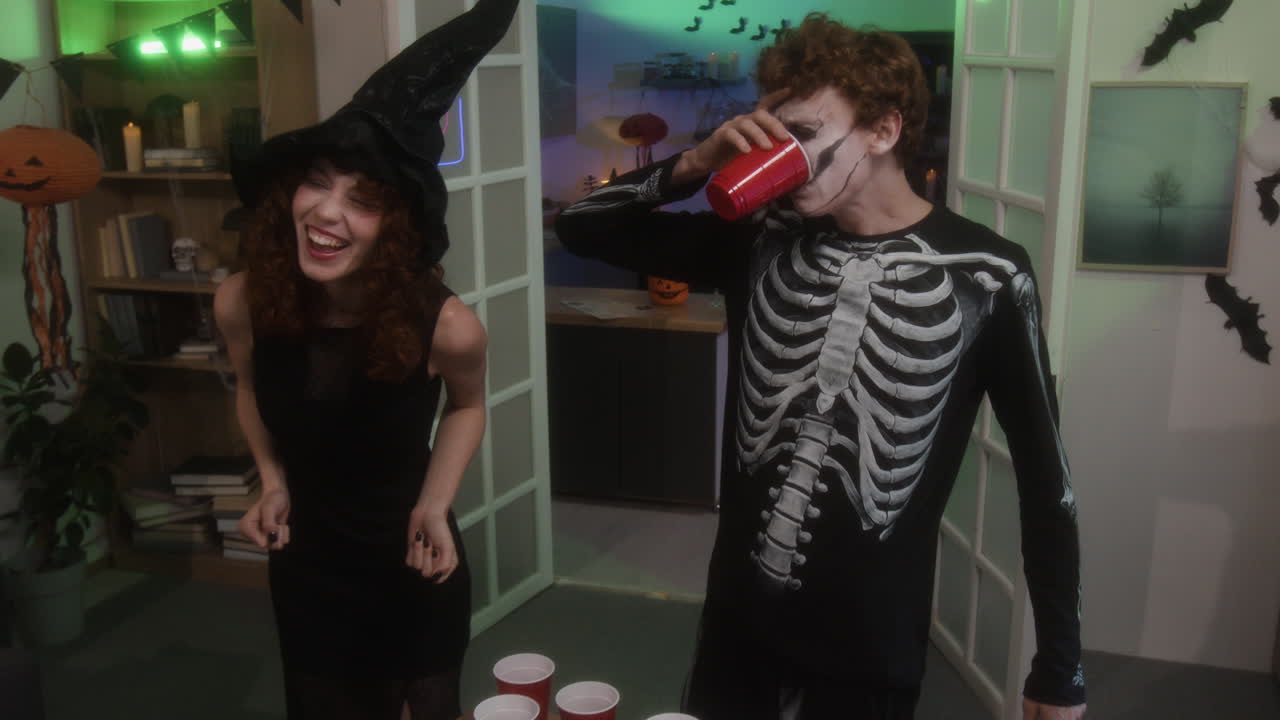 Halloween Party with People in Costumes Playing Beer Pong