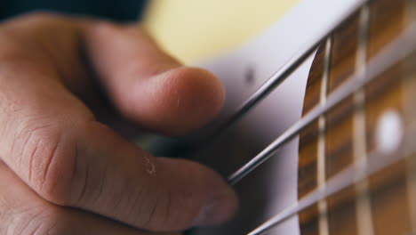 musician-plays-white-bass-guitar-with-metal-strings-closeup