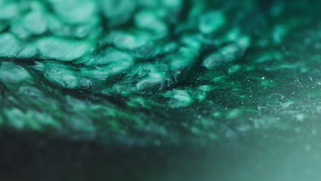 macro shot of green, cyan, dark green, grey, and blue ink flowing in fluid abstract motion, resembling a river