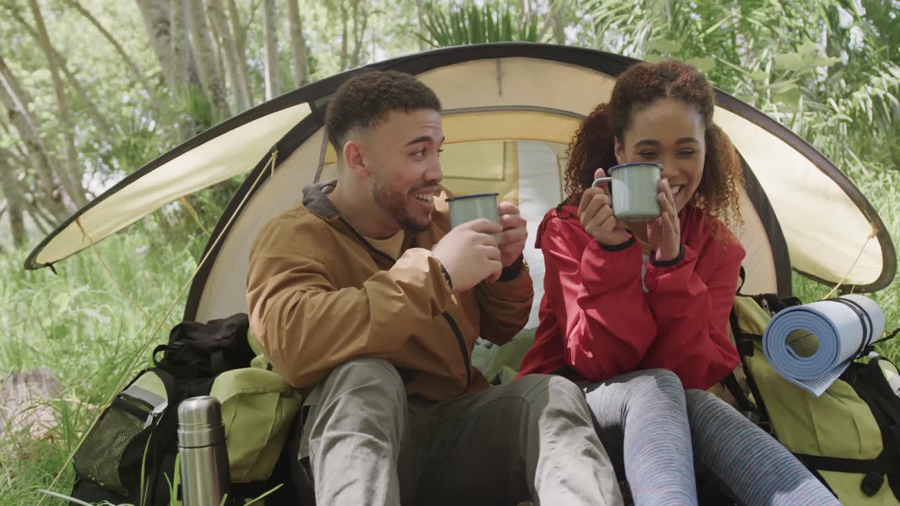 feliz pareja afroamericana acampando, bebiendo café en el bosque, cámara lenta