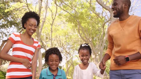 Linda-Familia-Se-Ríe-Y-Se-Toma-De-La-Mano-En-Un-Parque