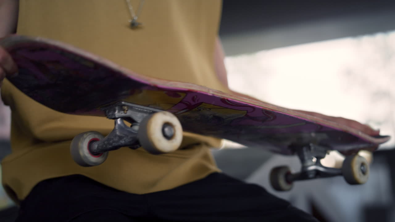 Casual skateboarder playing with skateboard in hands at urban skatepark.