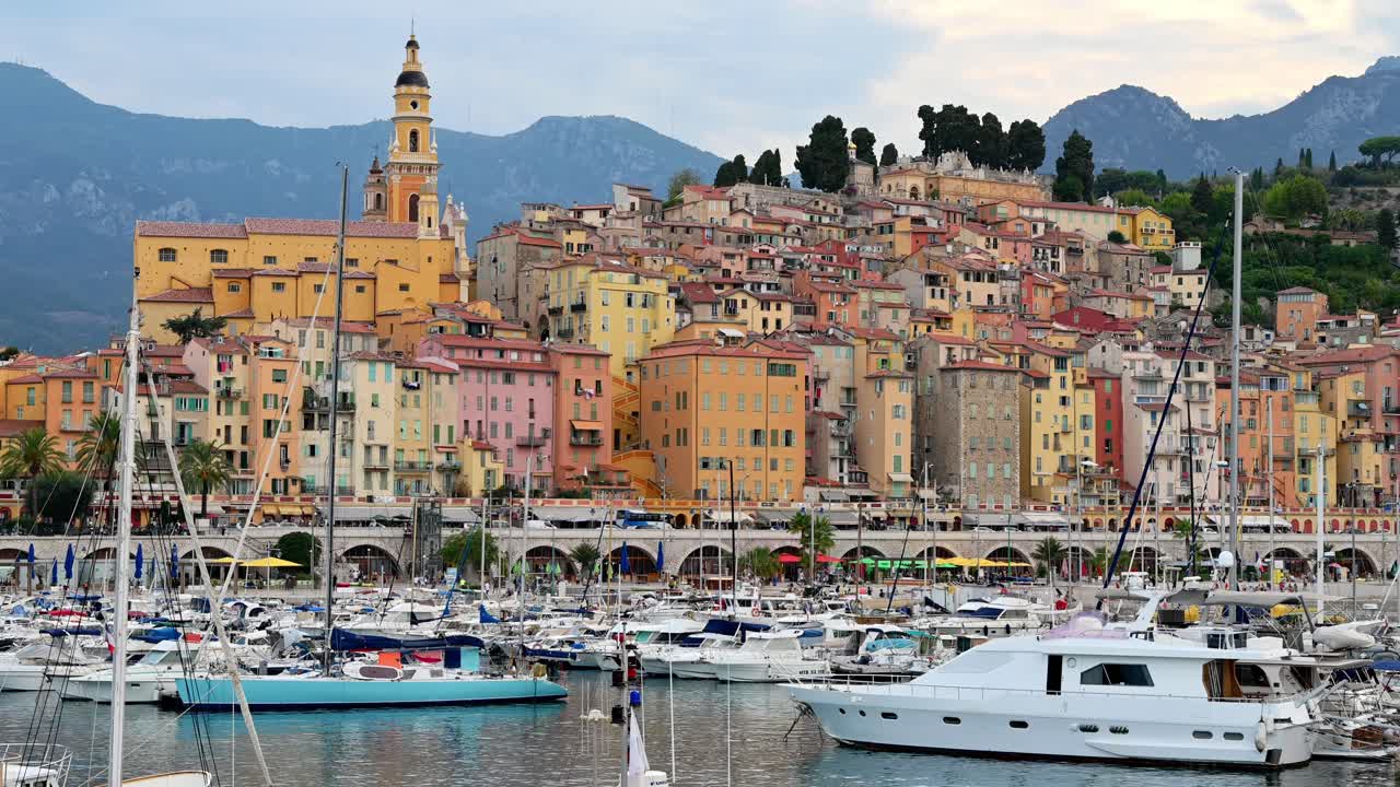 View of the sea port in Menton, France. Moored boats and yachts, Basilica St. Michel on the background, multiple buildings