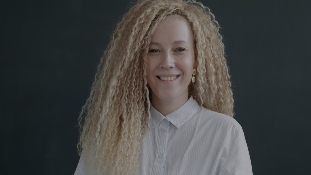 곱슬 머리카락을 가진 웃는 여성이 엄지손가락을 올리고 있습니다.