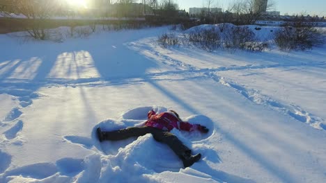 little girl making snow angel. winter children holiday