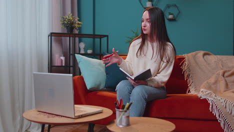 Adult-girl-student-study-at-home-on-laptop-computer-making-conference-video-call-talking-to-webcam