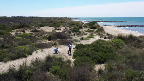 Zwei-Freiwillige-Umwelthelferinnen-Sammeln-Plastikteile-Mit-Einer-Stranddrohne-Ein