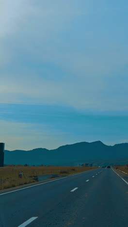 driving by the road crossing the valley at sunset. mountain range silhouette at backdrop. vertical video
