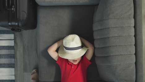 hands of mother pulling cute relaxed toddler in hat on sofa