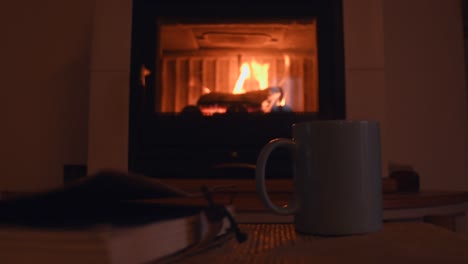 cozy background of a old notebook and a cup with hot steam getting out of it, near a warm fireplace