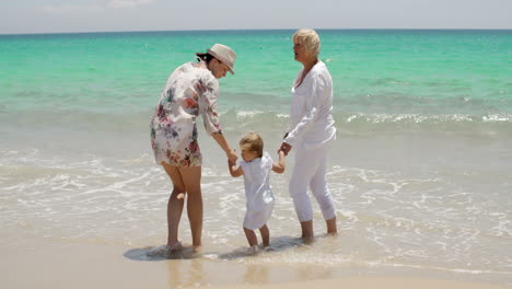 Oma-Und-Mama-Halten-Kleines-Mädchen-Am-Strand