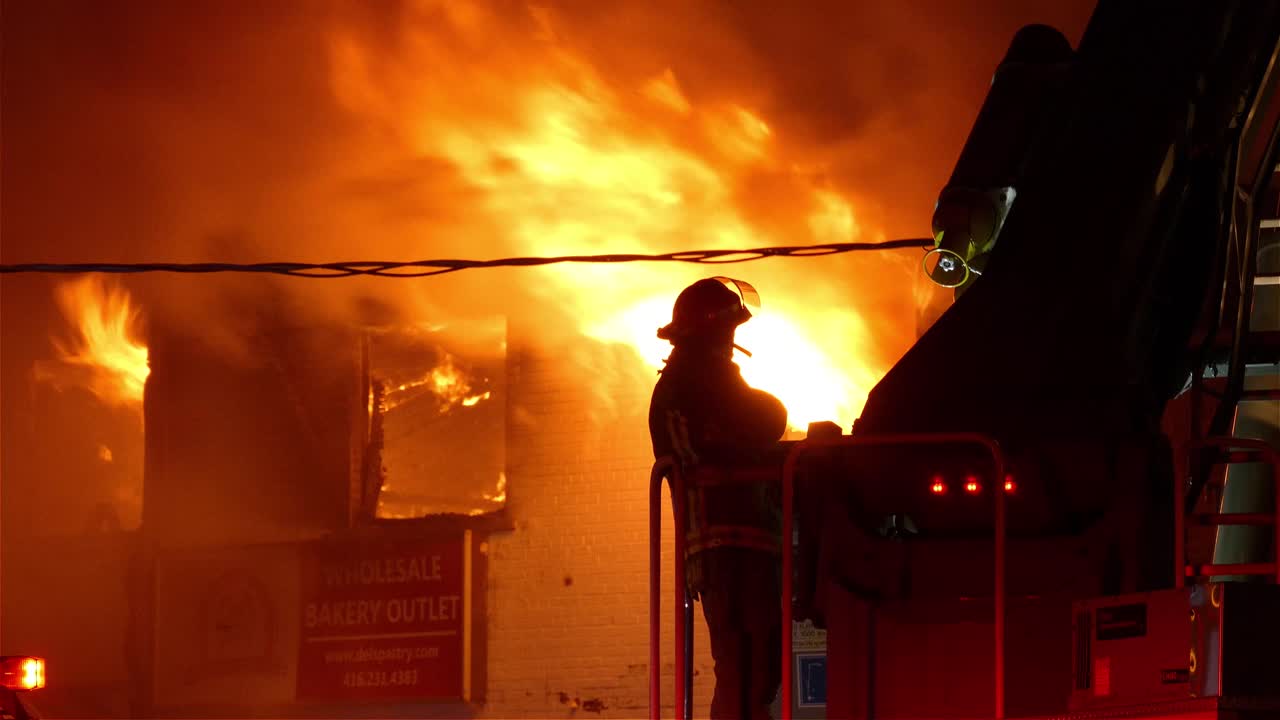 Silhouette of hero firefighter against blazing hell trying to extinguish