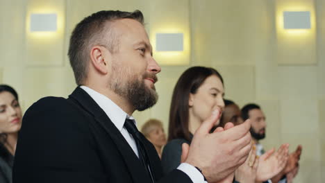 close-up de mãos de empresário caucasiano batendo palmas entre o público em uma sala de conferências