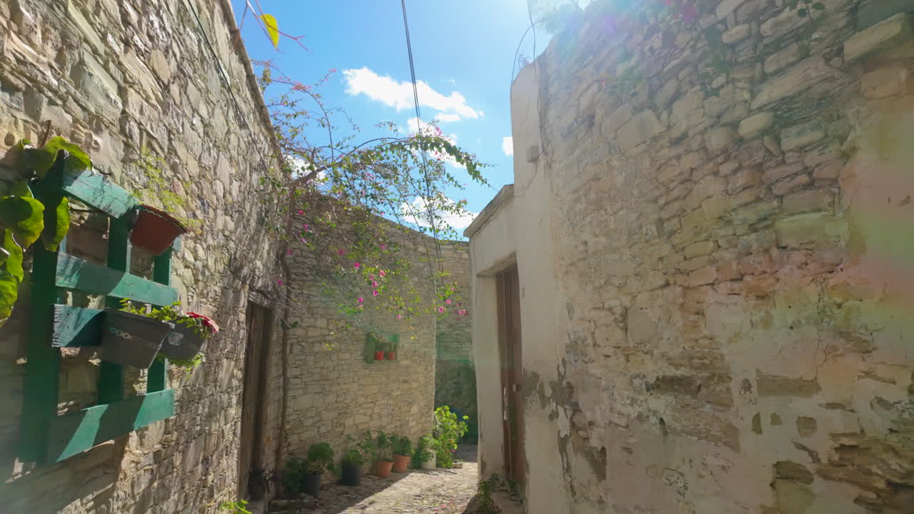 Vicolo in pietra a Lefkara con bouganville fiorita che si inarca sopra e dettagli architettonici tradizionali mediterranei.