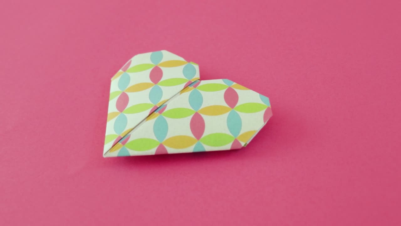 Folded decorative origami heart on pink paper for Valentine's day