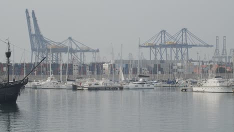 ferdinand magellan nao victoria carrack boat replica with spanish flag going into harbour in valencia with cranes in the background in slow motion 60fps