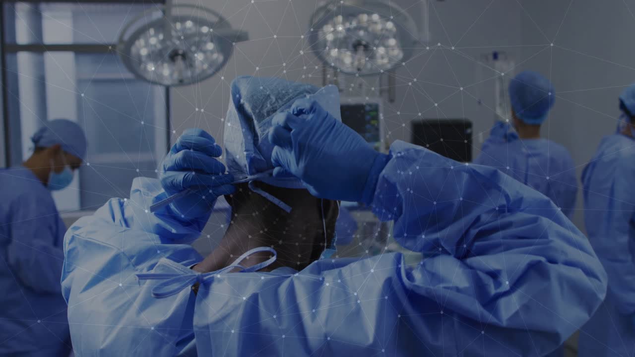 Ledende kirurg binder hue før medicinsk operation under lys, mens kolleger overvåger vitale funktioner.