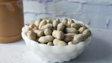 cacahuetes en un tazón con un frasco de mantequilla de maní