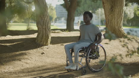 Young Black Man Riding His Wheelchair In Park On Sunny Day