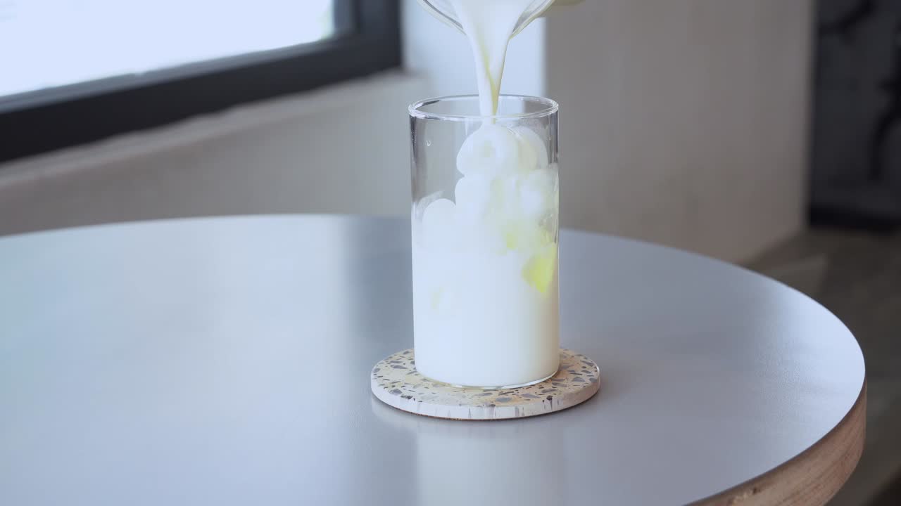 concepto de publicidad de restaurante de café cinematográfico, solución diaria de cafeína, un vaso de café con leche helado con cubitos de hielo, agregando leche fresca y café expreso y bien revuelto con una pajita de vidrio