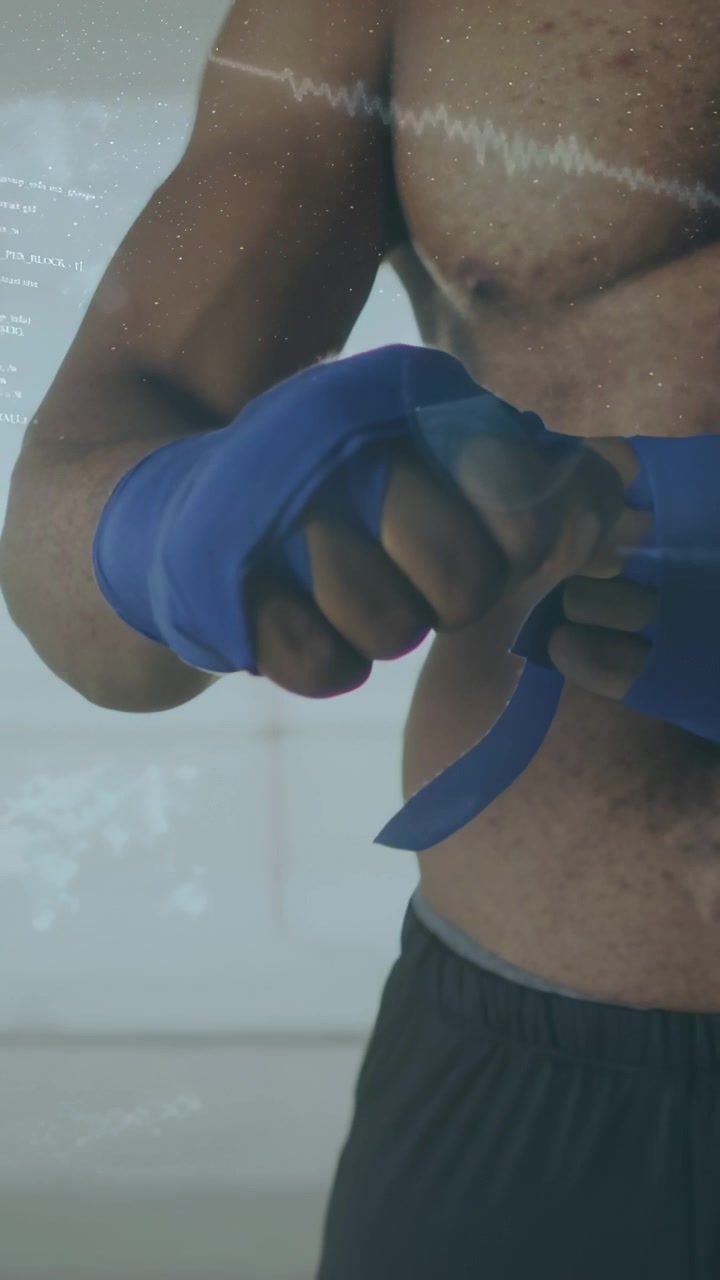 Video verticale: Un pugile si avvolge bende blu alle mani in palestra, stringendo nocche e polsi prima di boxare.