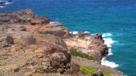 rocky cliffs on the mountain of maui with nakalele blowhole exploding on rocks in the background with pacific ocean in maui, hawaii, united states