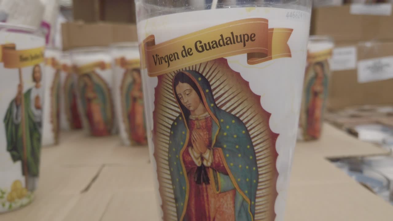 Primo piano di una candela della Madonna di Guadalupe in un negozio, in interni, ripresa con panoramica verso l'alto