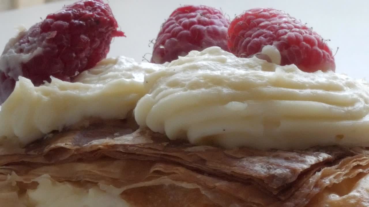 Flaky millefeuille dessert with creamy filling and fresh raspberries on top