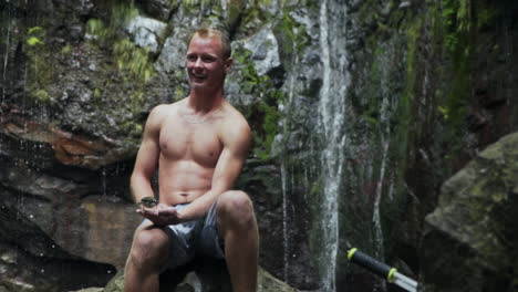 small bird eats out of delighted young man's hand in rain forest, slow motion