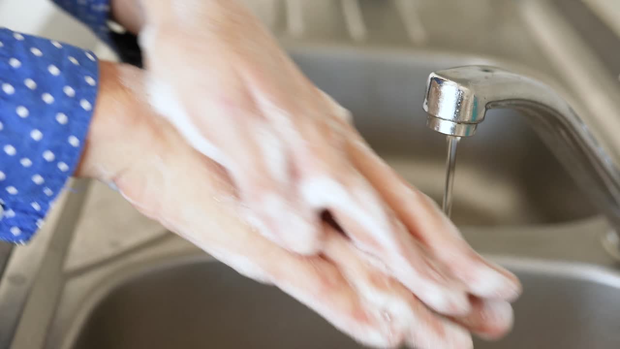 Kvinne vasker hendene sine med såpe hjemme