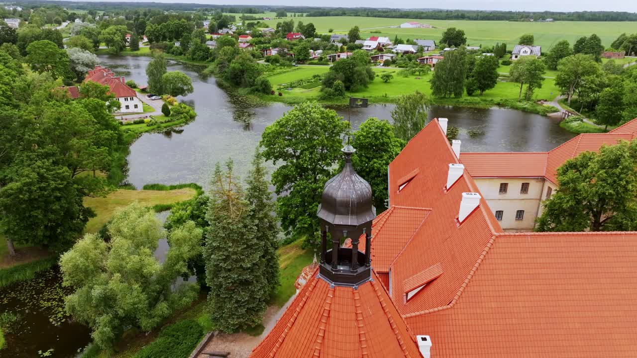 Peaceful aerial view of Jaunpils Castle, mill pond, Bikstupe in cloudy daylight