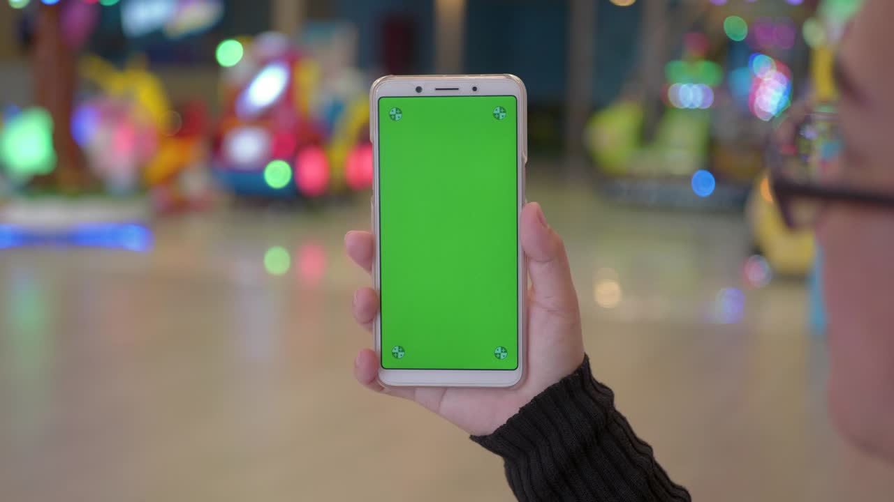 mujer asiática mano usando un teléfono inteligente con pantalla verde en el centro comercial.