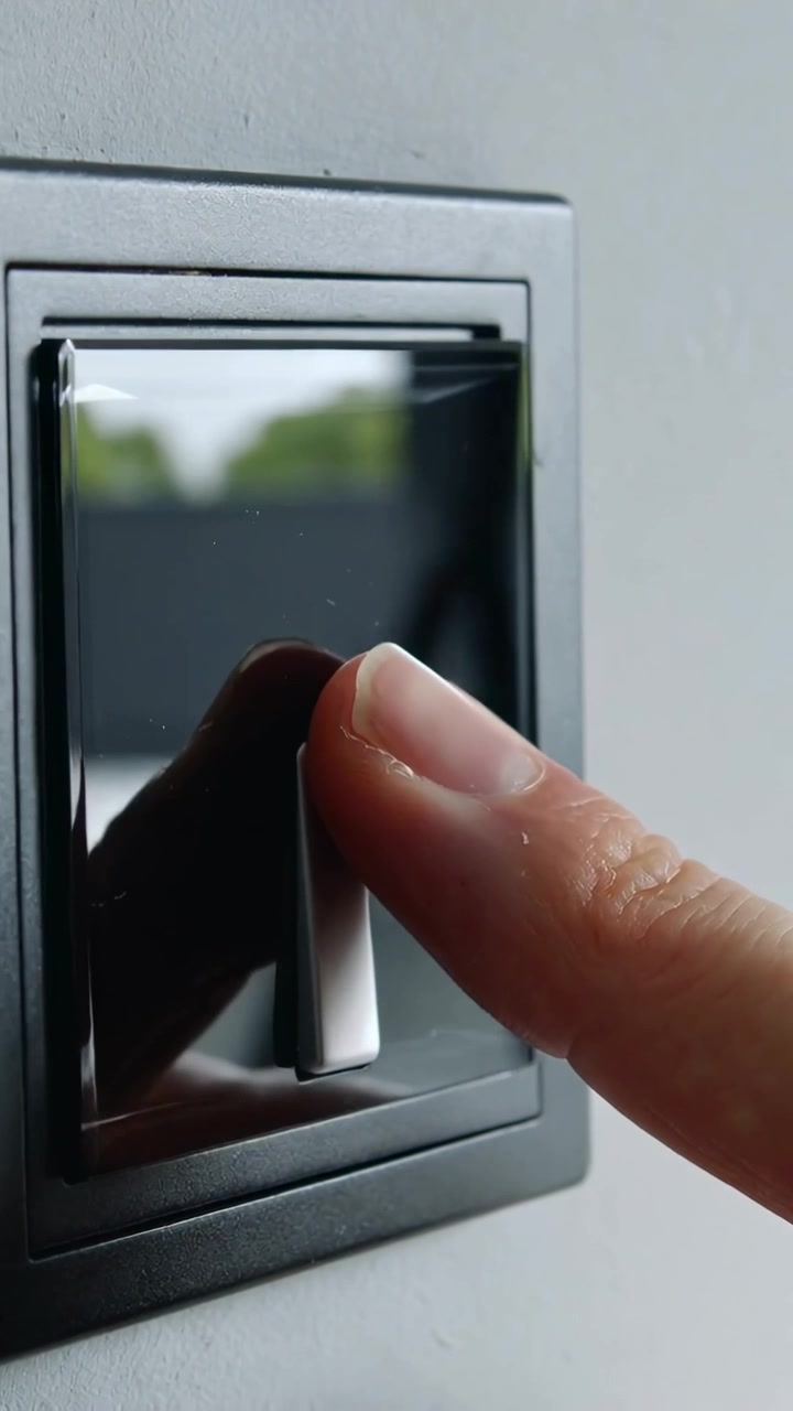 Vertical video: Approaching fingertip pressing rocker switch at home, toggling light, showing view