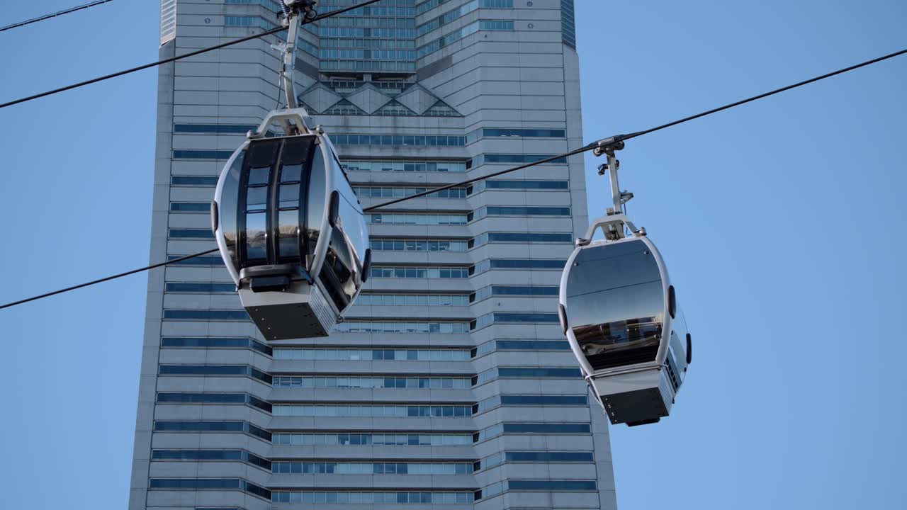 Primo piano della gondola Yokohama Air Cabin, la prima funivia urbana del Giappone, che passa davanti alla Landmark Tower a Minato Mirai in una giornata limpida e soleggiata, una popolare attrazione turistica